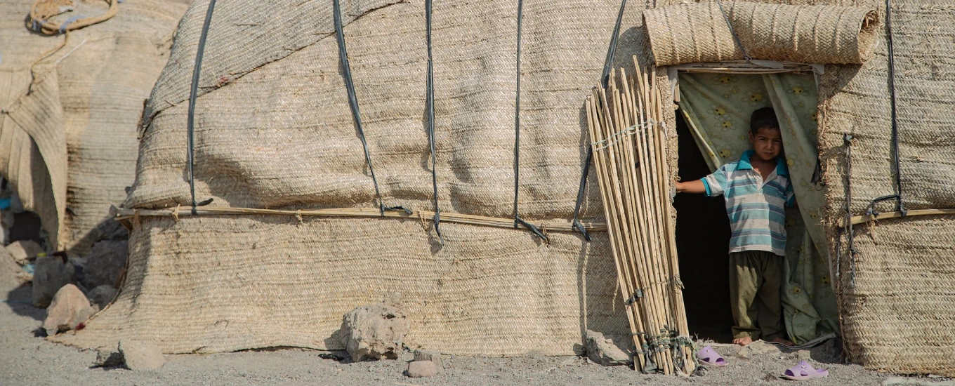 Community member standing in doorway of traditional dwelling in conflict-affected region